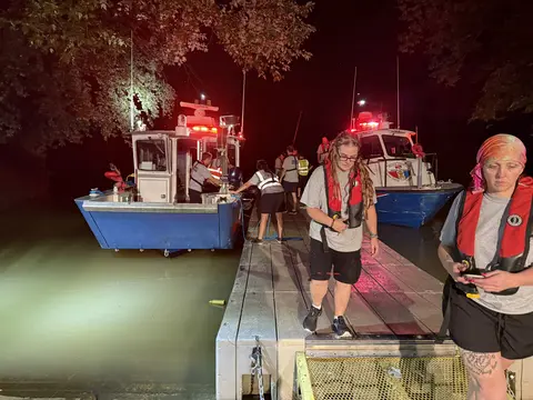 Team members loading rescue vessels at night.